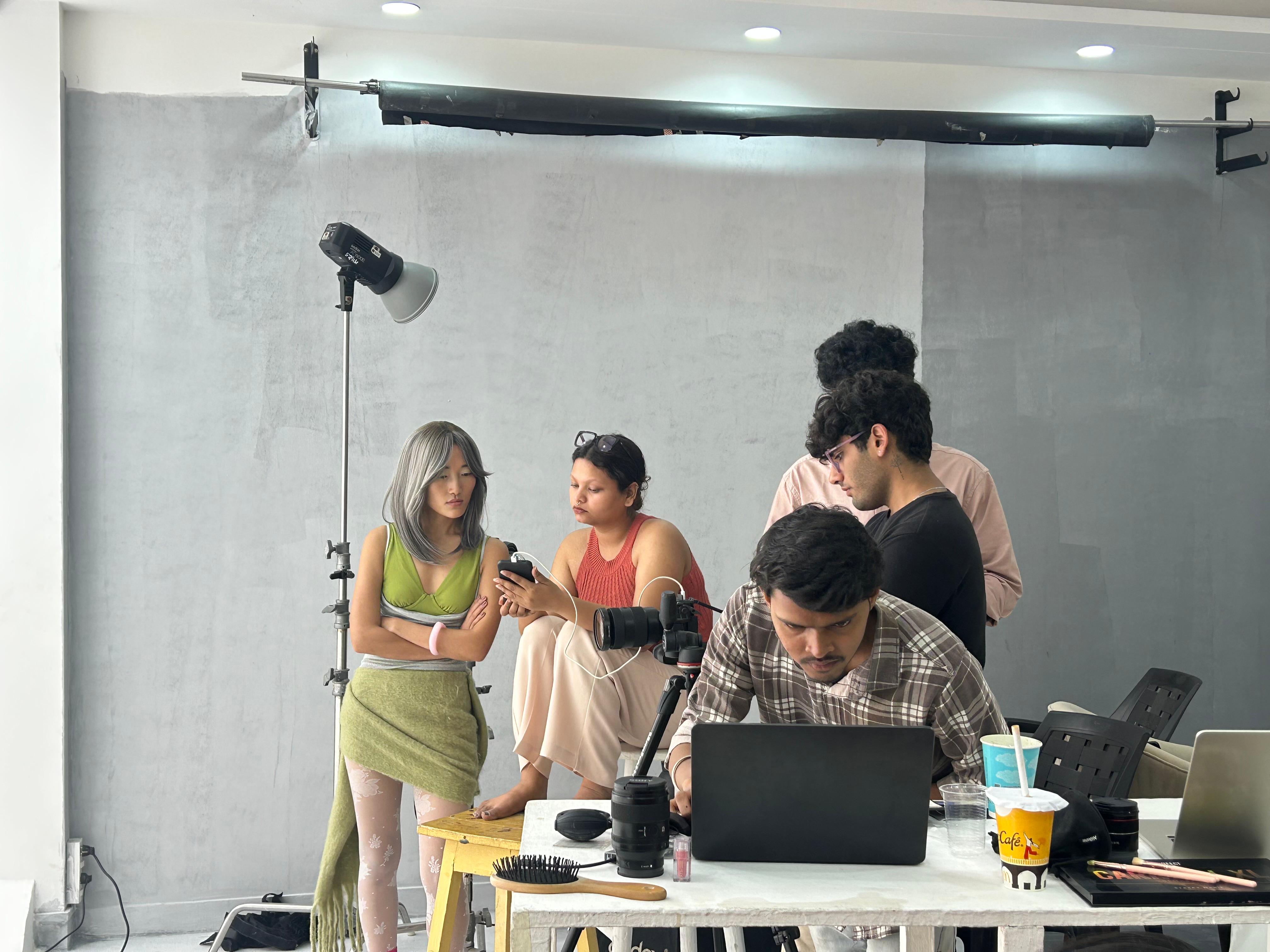 Team gathered around laptop reviewing direction on set